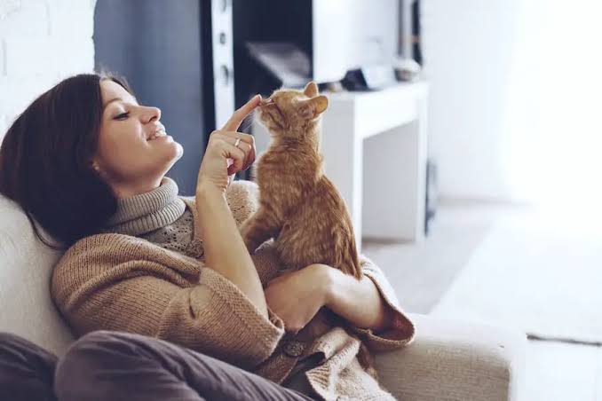 A woman plays with a cat during her pet sitting